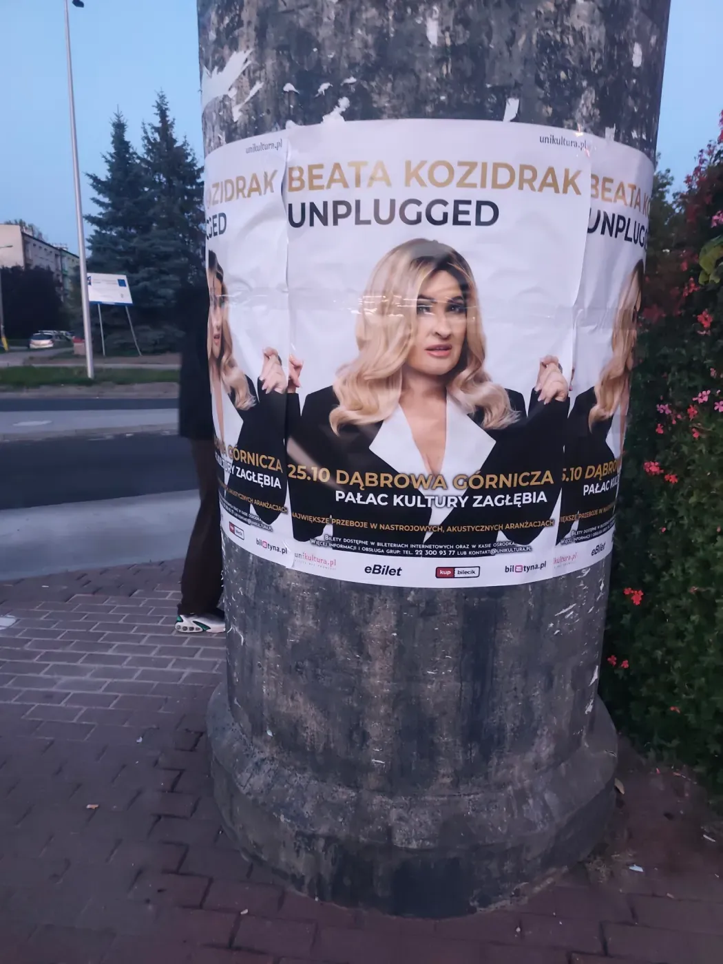 Plakaty Beata Kozidrak Unplugged na okrągłym słupie ogłoszeniowym przy chodniku