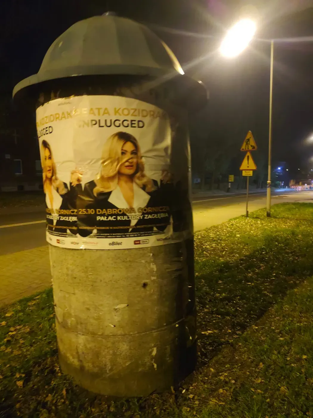 Plakat Beata Kozidrak Unplugged na słupie przy oświetlonej ulicy w Katowicach