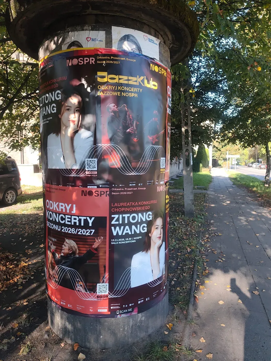 Słup ogłoszeniowy z plakatami koncertowymi przy chodniku w katowickiej dzielnicy