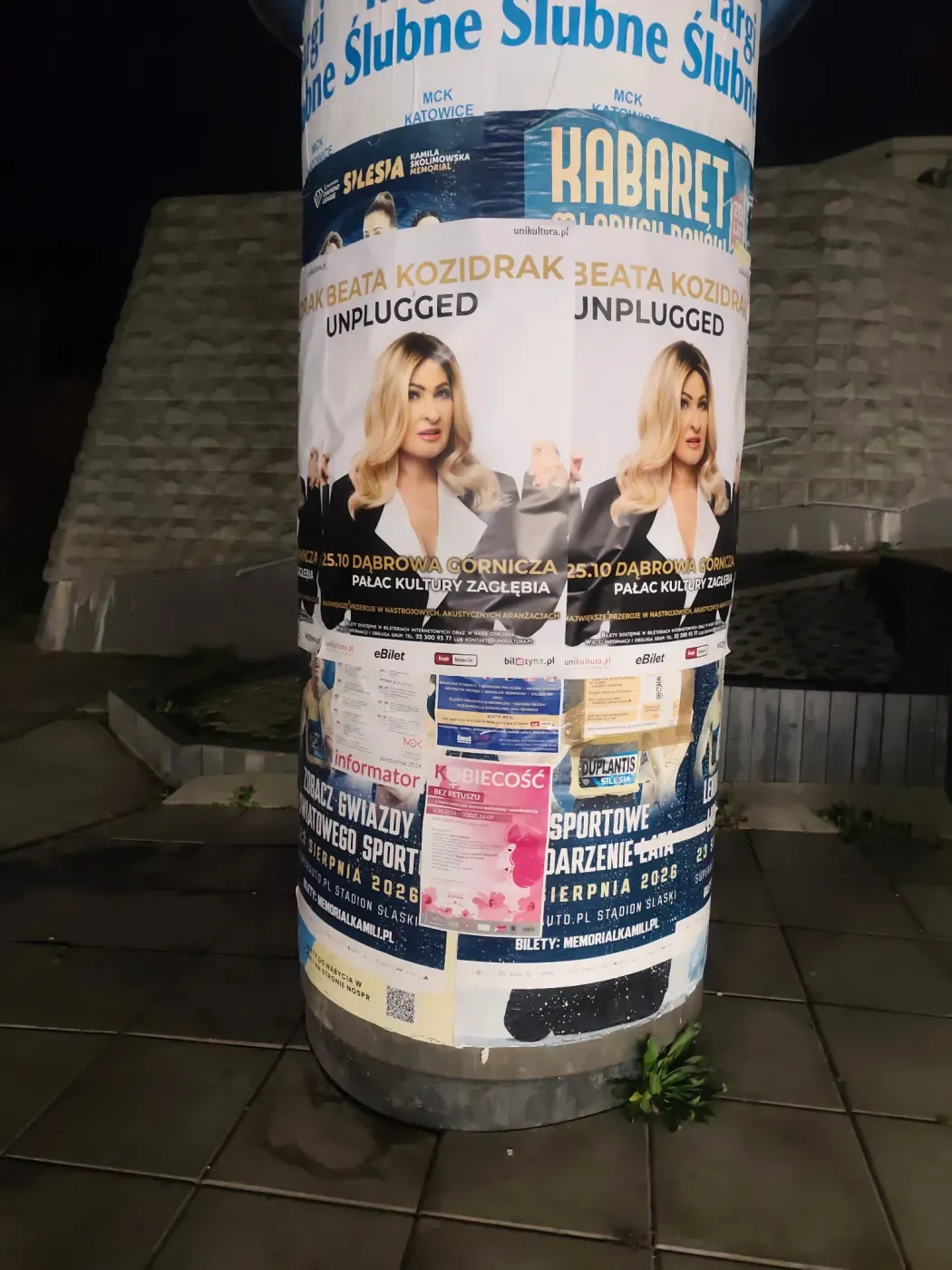 Okrągły słup ogłoszeniowy z plakatami koncertu i innymi afiszami