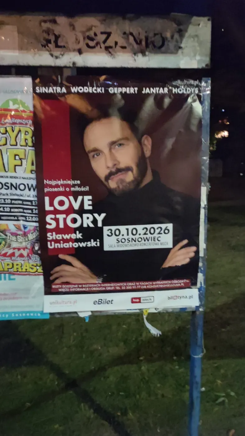 Plakat Love Story Sławka Uniatowskiego przyklejony na miejskiej tablicy ogłoszeniowej.