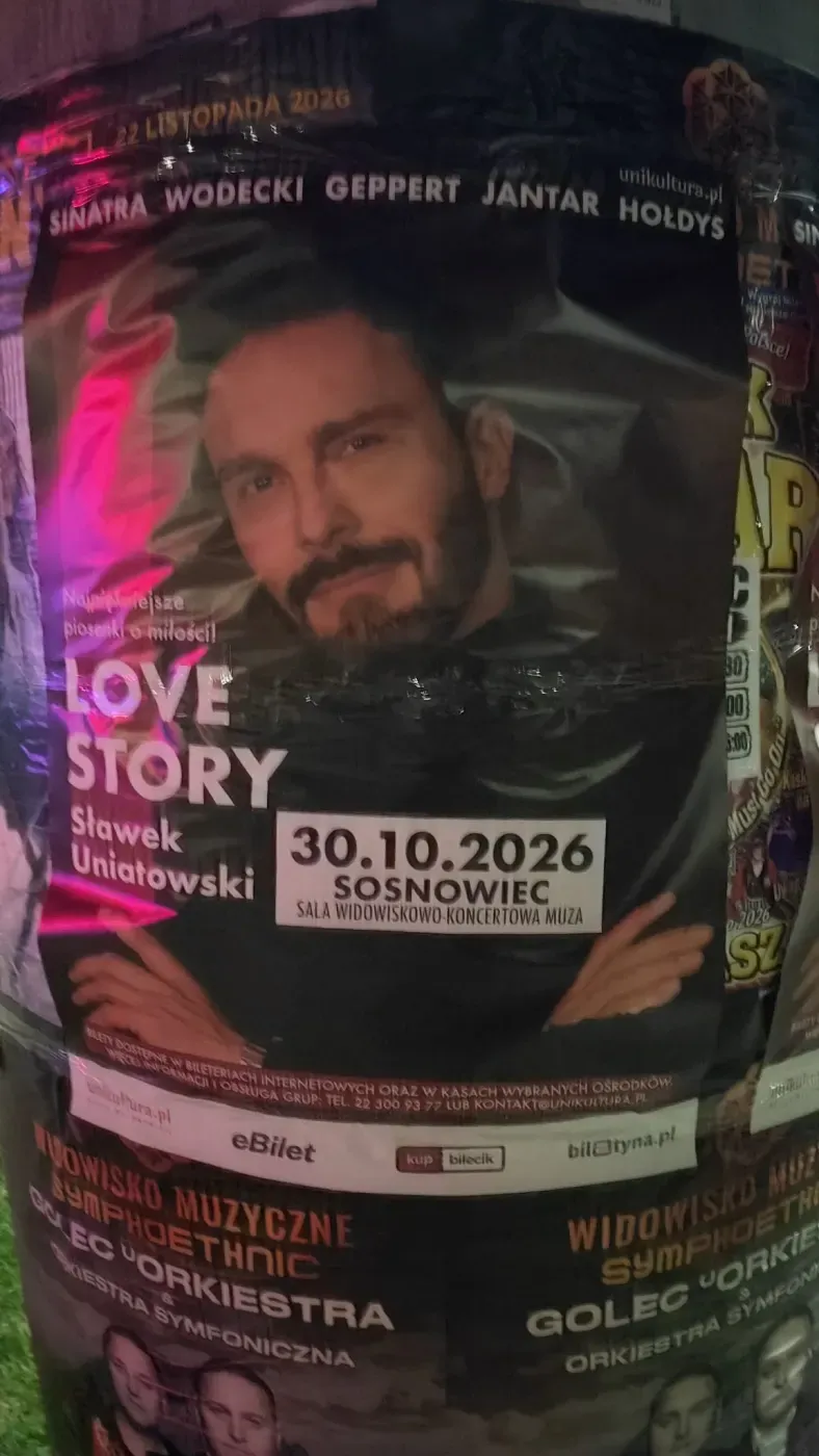 Zbliżenie plakatu Love Story z twarzą Sławka Uniatowskiego i datą koncertu w Sosnowcu.