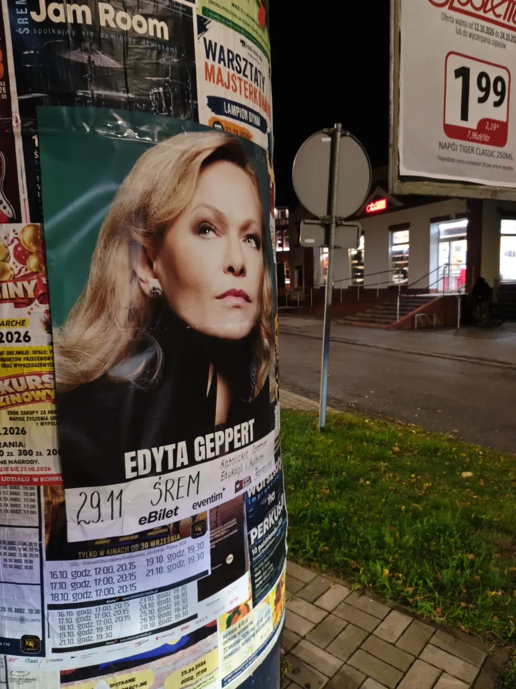 Zbliżenie plakatu Edyty Geppert na słupie ogłoszeniowym przy sklepie i ulicy